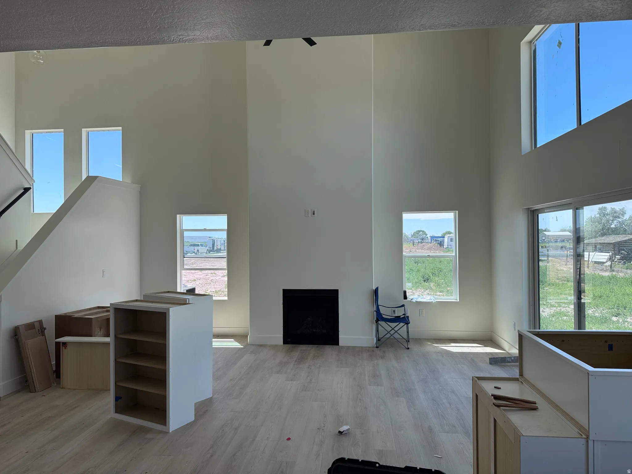 Two-story open-concept living space with high ceilings, light wood-finish flooring, and a contemporary fireplace
