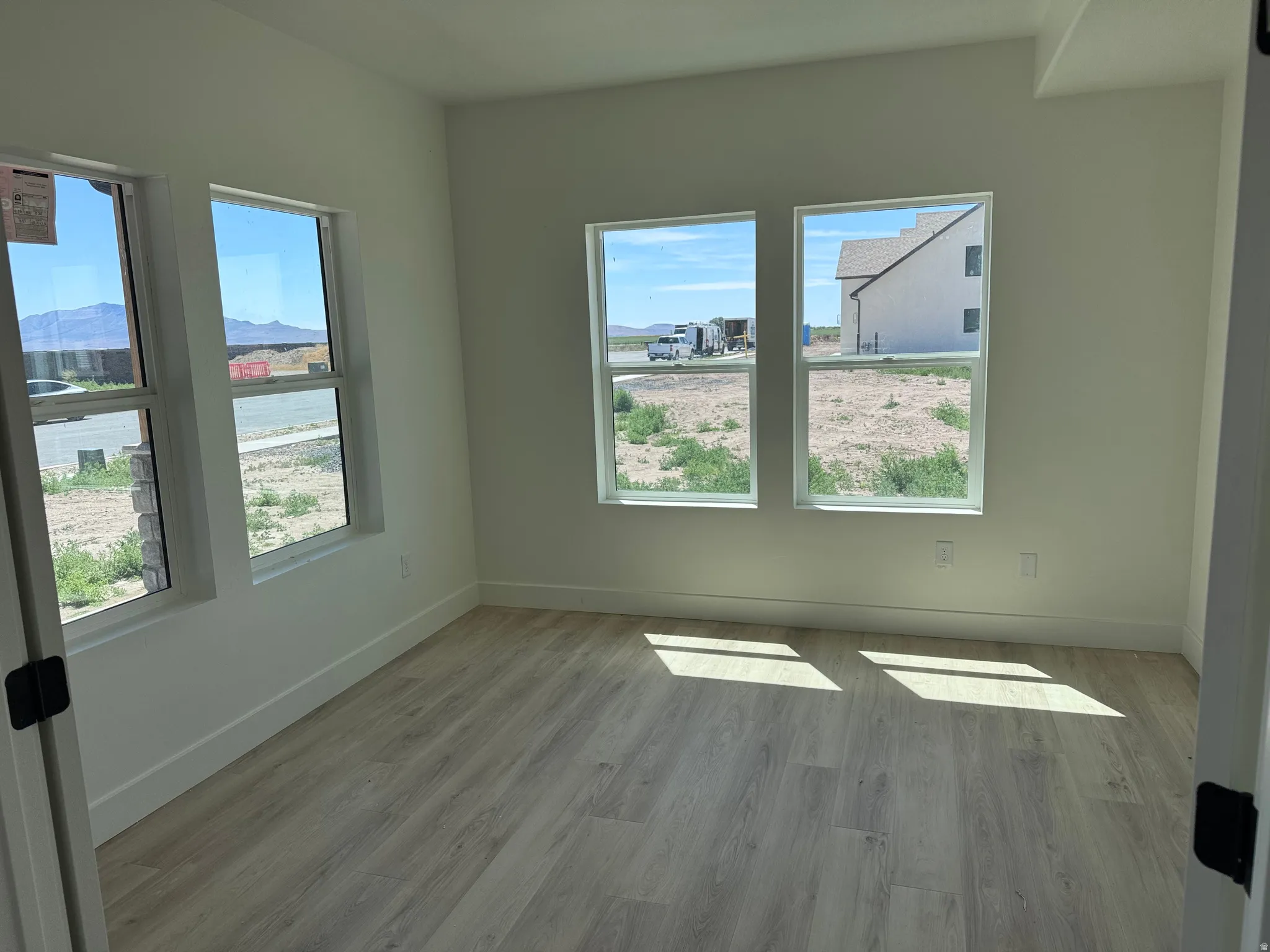Room featuring light wood-finish flooring, white walls, and multiple windows