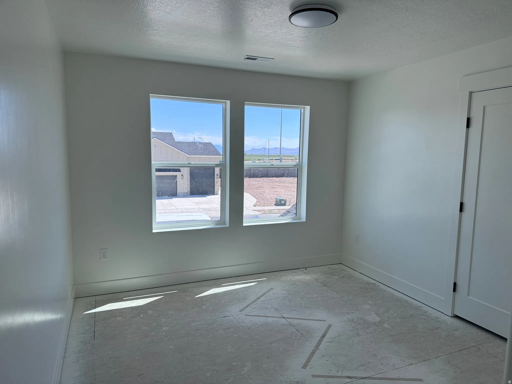 Bright interior space featuring two windows, a contemporary flush-mount ceiling light fixture, baseboard trim, and a paneled interior door