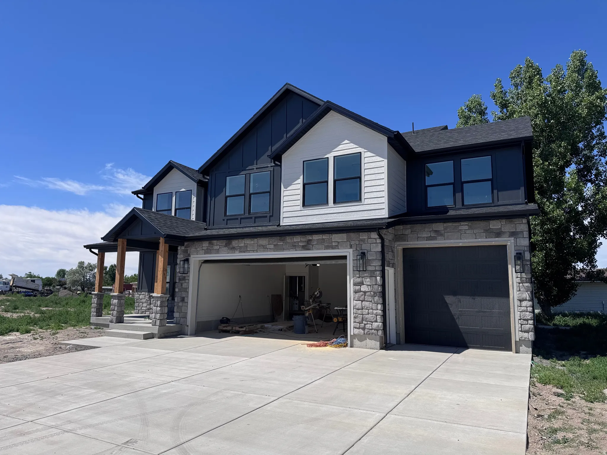 Contemporary exterior featuring stone veneer, dark siding, and white paneling accents