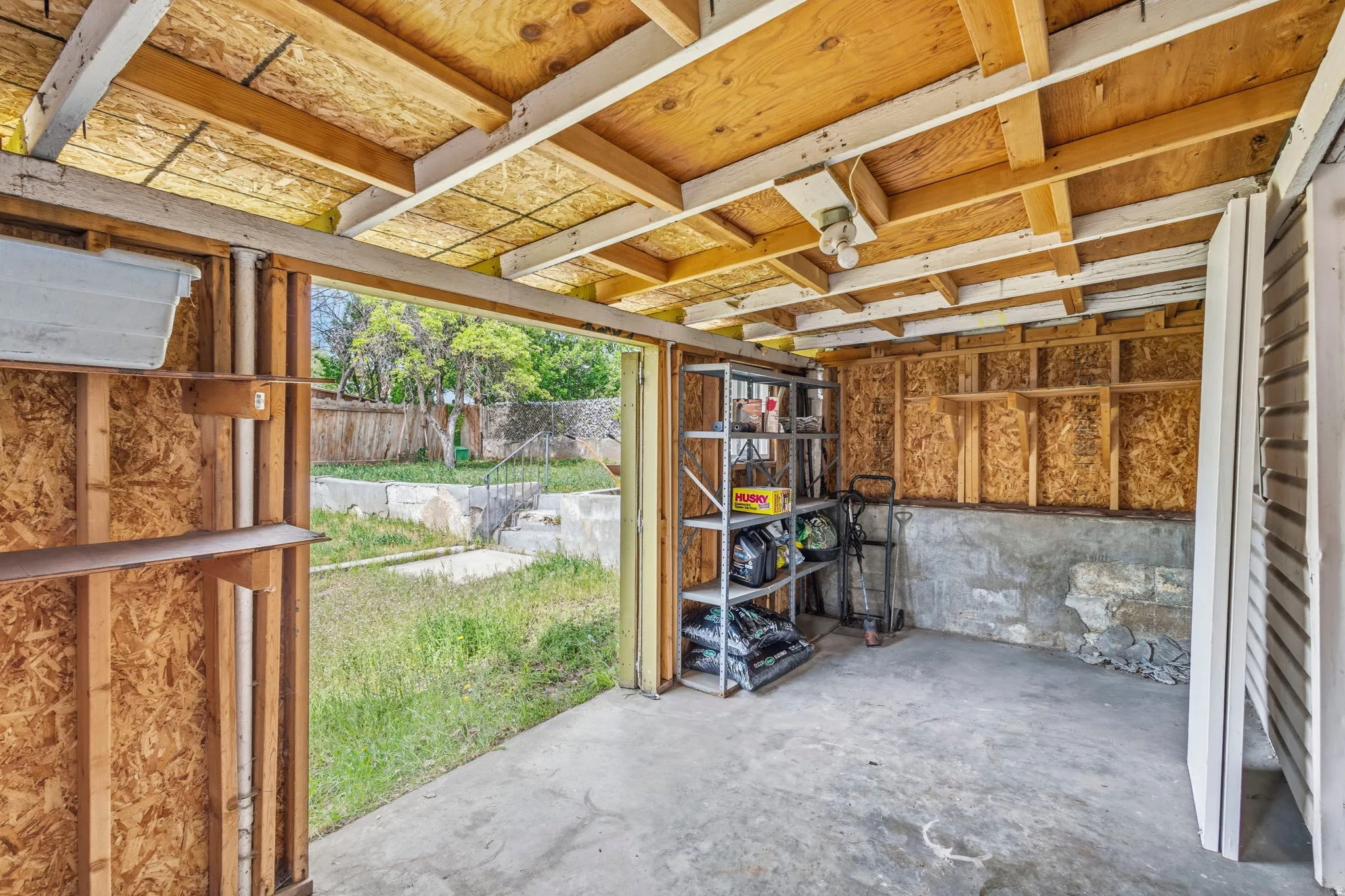 Open-air structure with exposed wood framing and a concrete floor