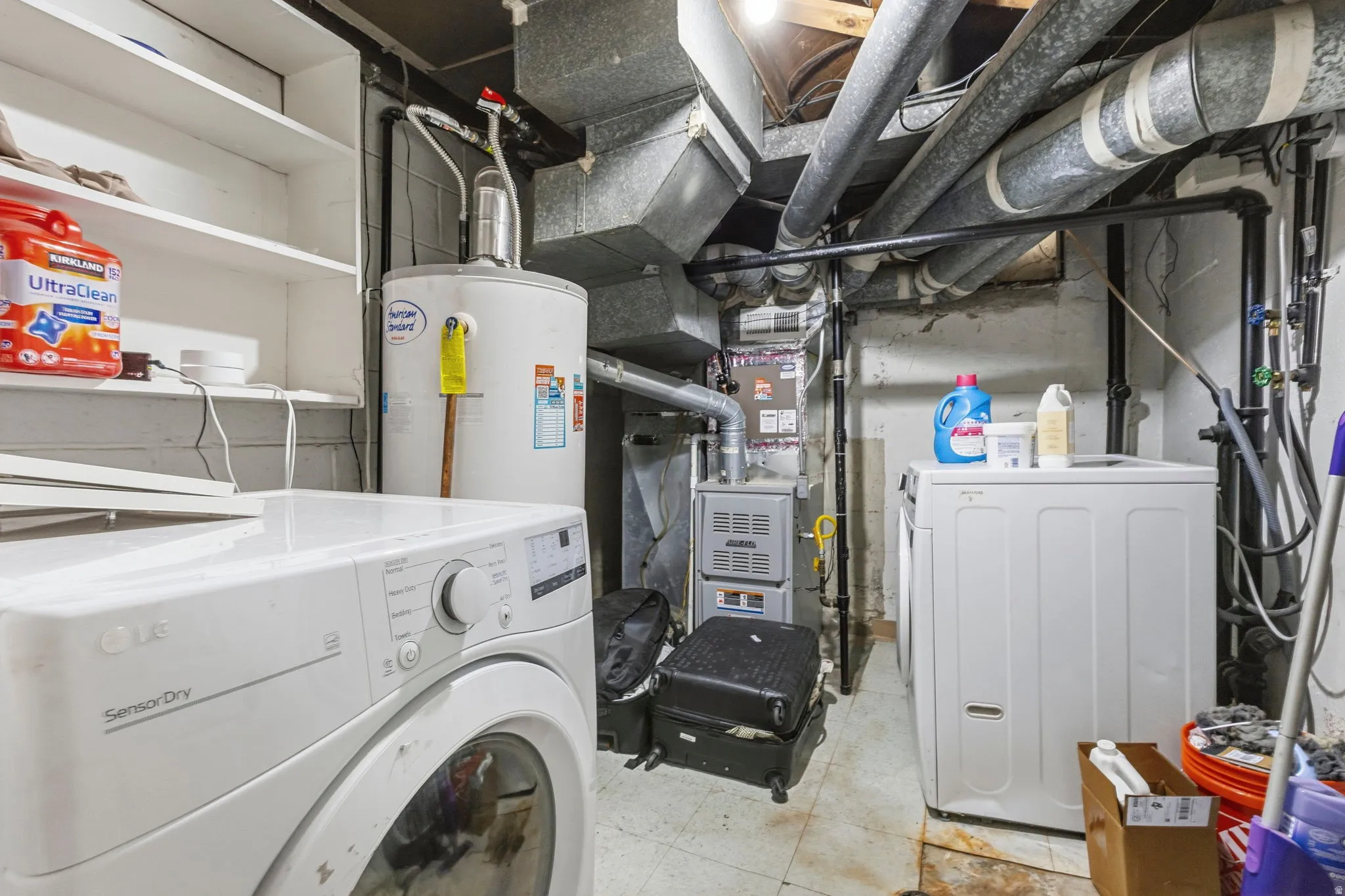 Dedicated utility space featuring laundry appliances, a water heater, furnace, and built-in shelving for storage