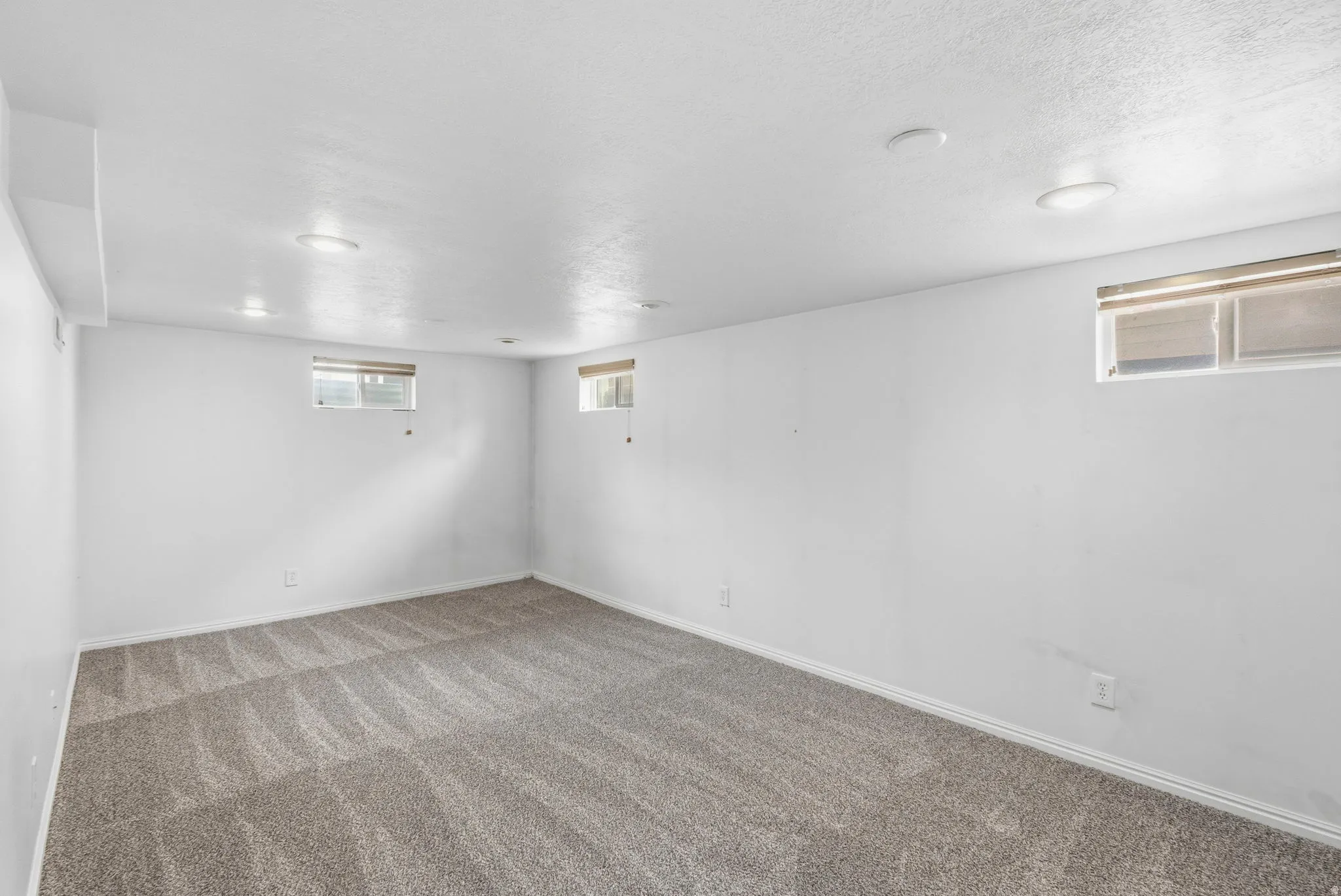 Spacious room featuring new carpeting, multiple windows, and recessed lighting for ample illumination