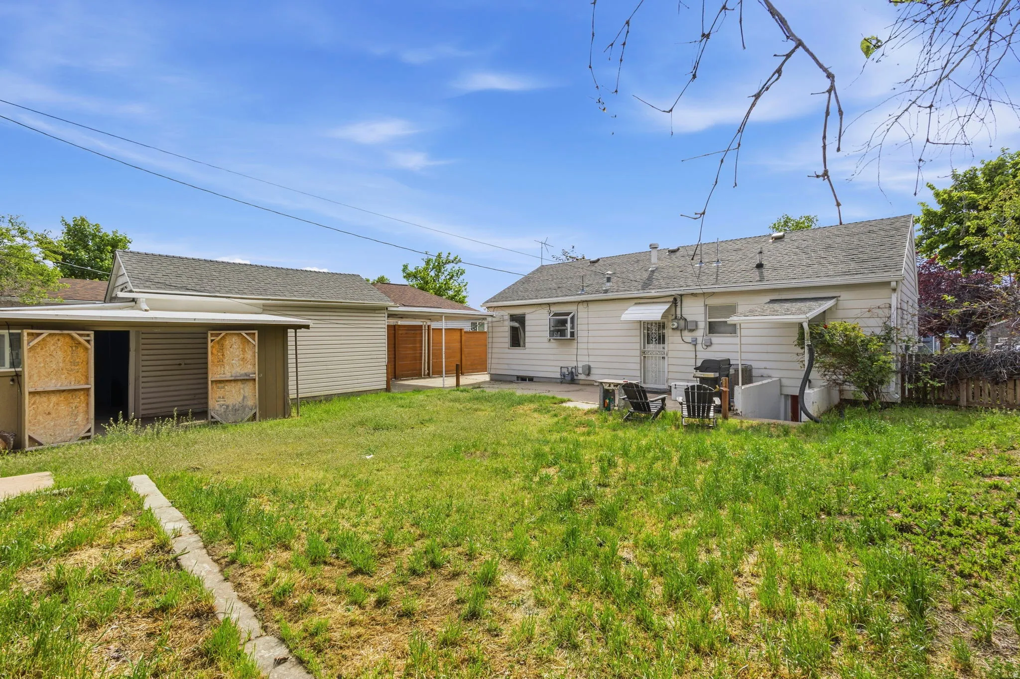 Expansive backyard featuring a concrete patio, a detached garage with a side storage shed, and a privacy fence