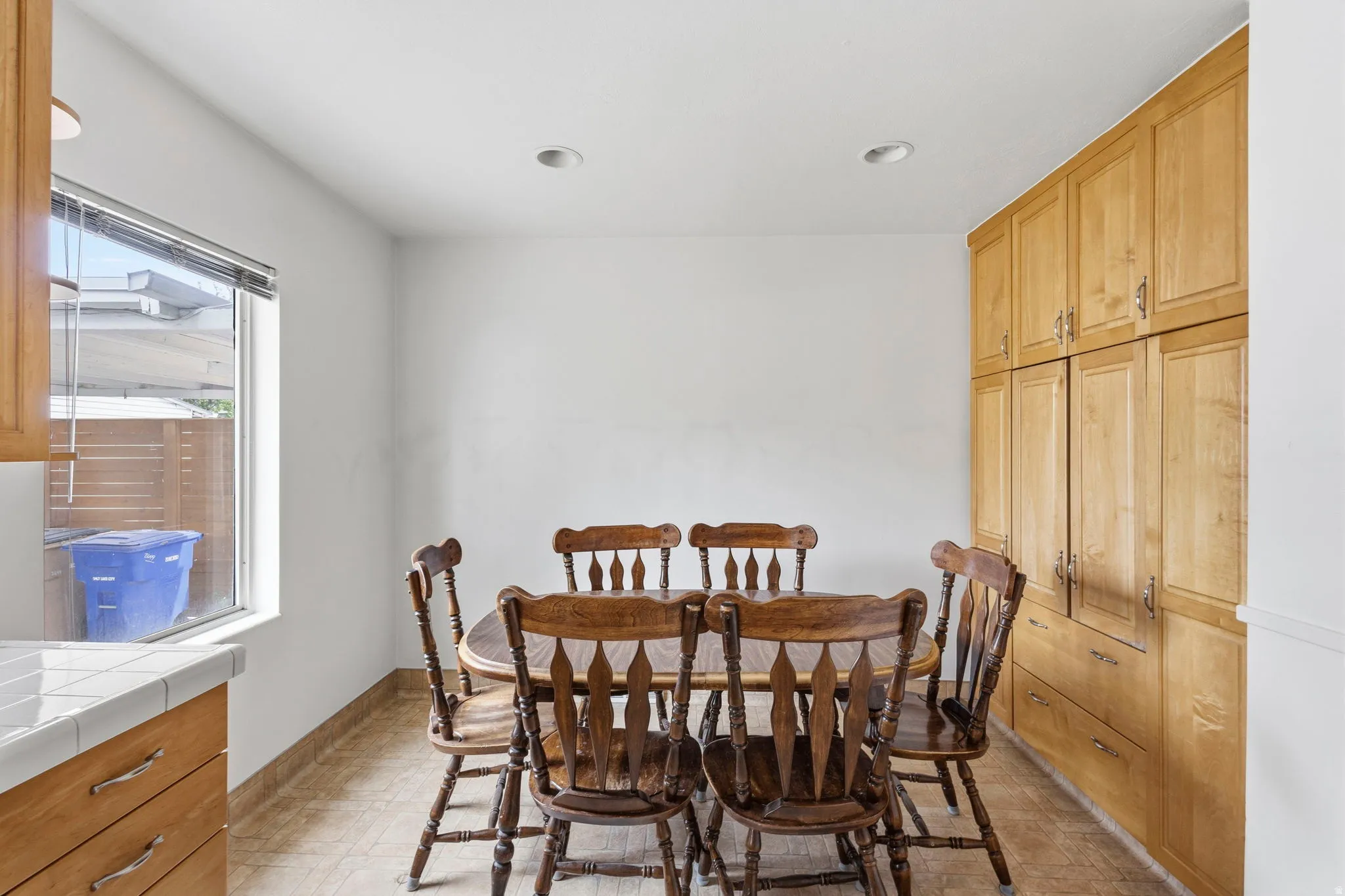 Built-in cabinetry providing extensive storage in a bright dining area featuring recessed lighting, tile flooring, and a window for natural light
