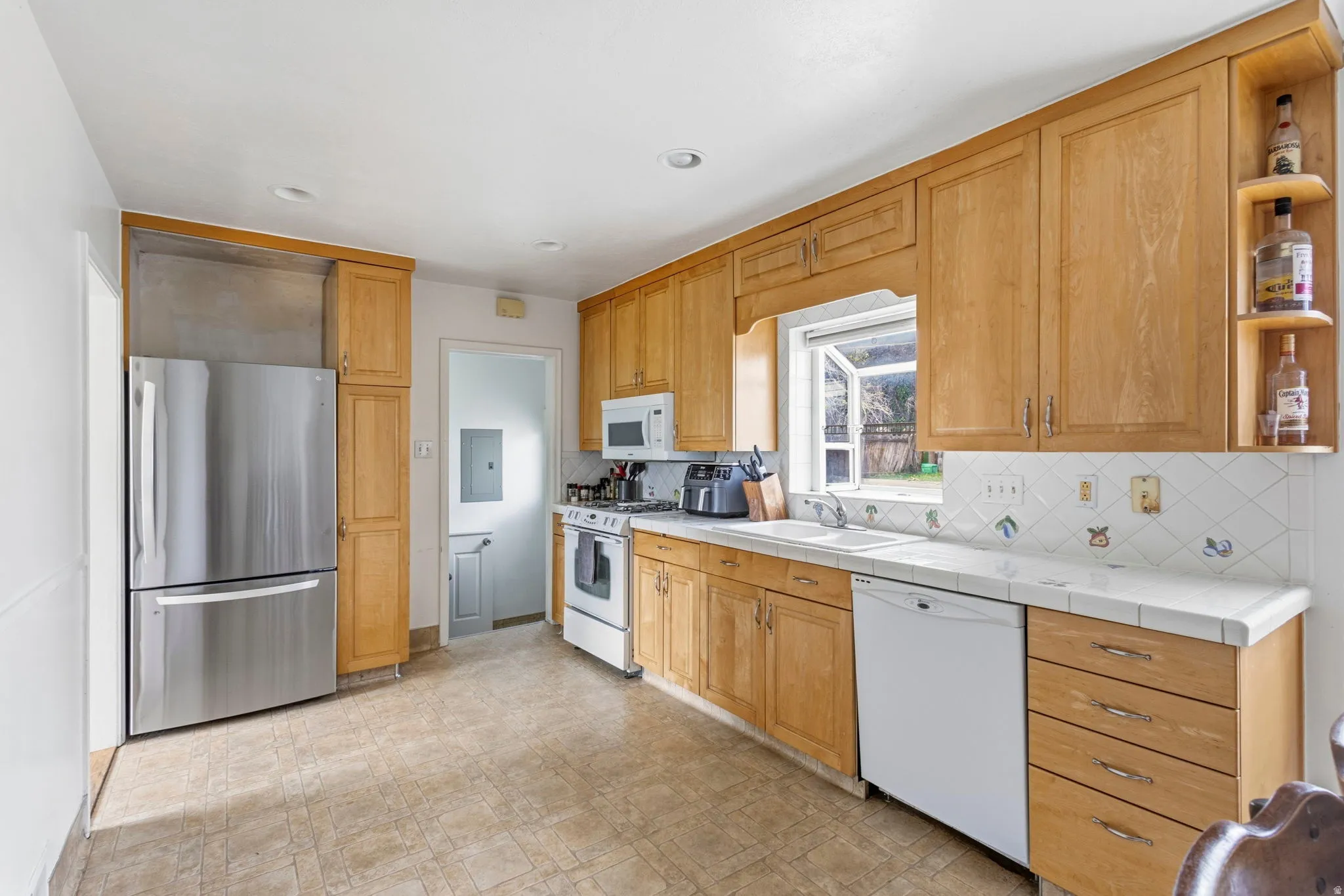 Kitchen featuring wood cabinetry, a tile countertop, and a white tile backsplash with decorative accents