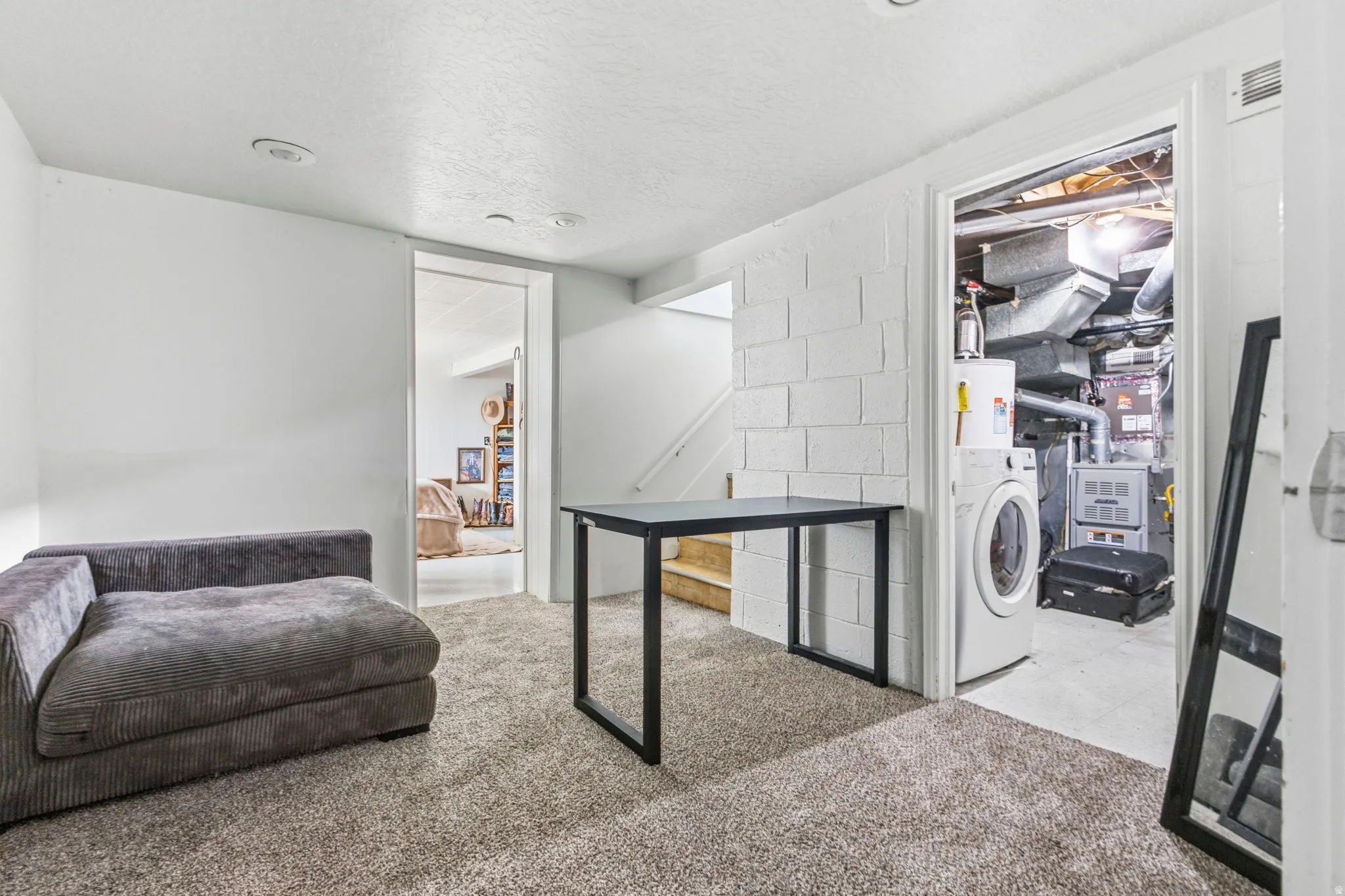 Carpeted interior space featuring white painted walls, recessed lighting, and a utility closet with a washer and water heater