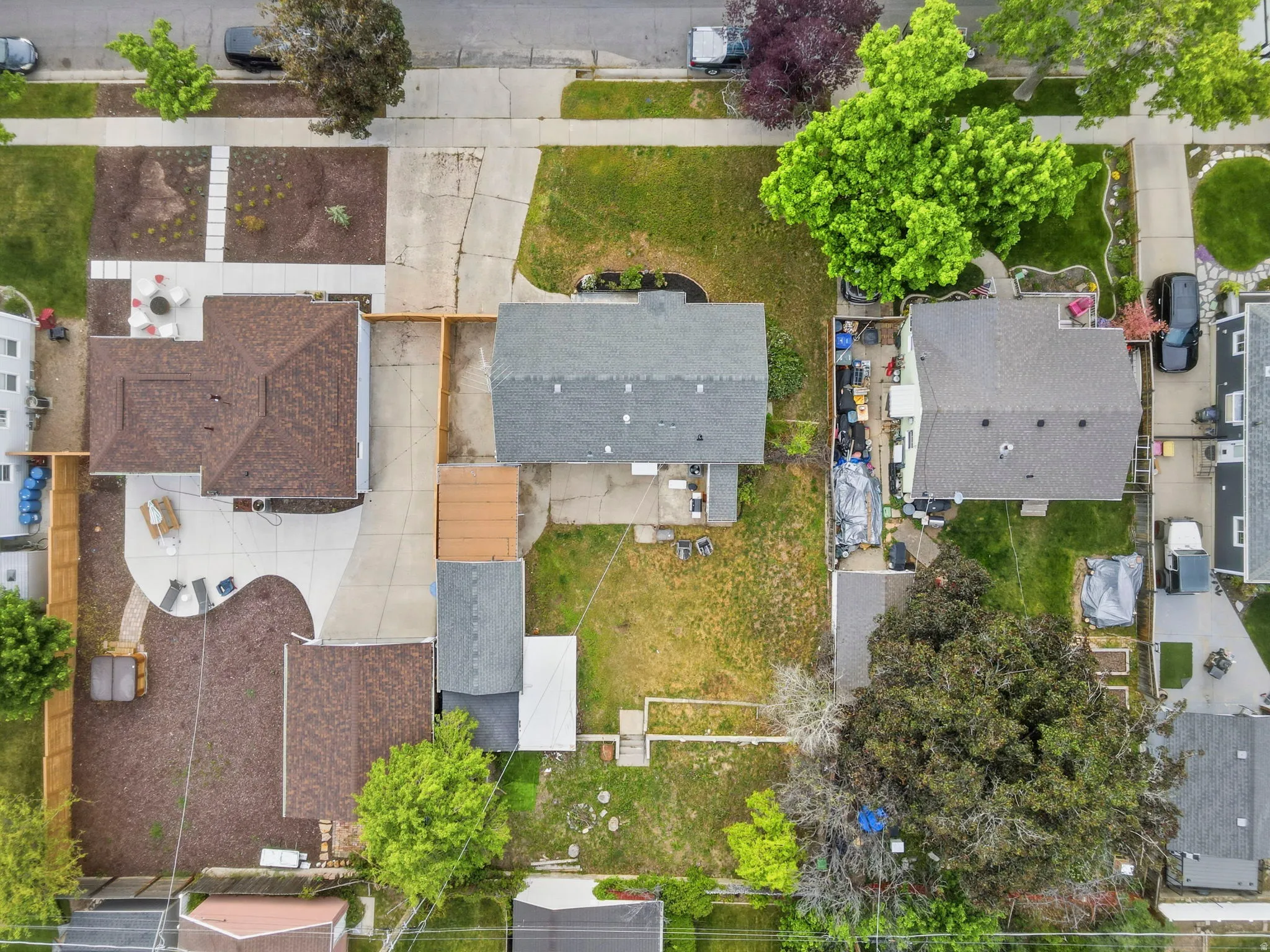 Expansive lot featuring two residential structures with shingle roofs, concrete driveways, and mature landscaping
