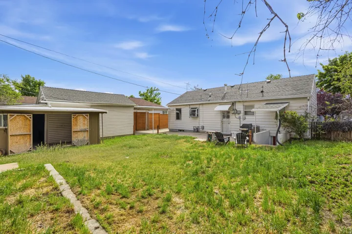 Expansive backyard featuring a concrete patio, a detached garage with a side storage shed, and a privacy fence
