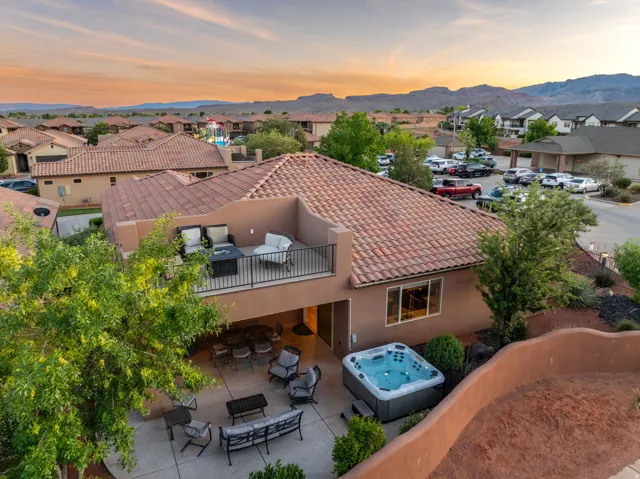 Back of house at dusk with a hot tub, a residential view, stucco siding, a balcony, and a patio area