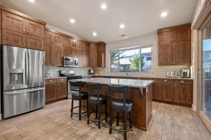 Kitchen with stainless steel appliances, light stone countertops, a breakfast bar area, lofted ceiling, and a kitchen island