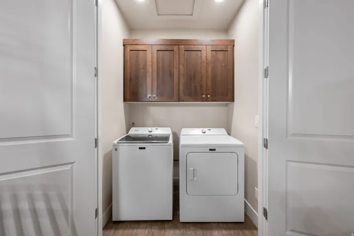 Laundry area featuring cabinet space, independent washer and dryer, and dark wood-style flooring
