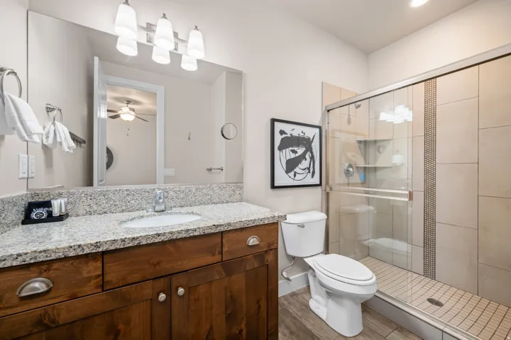 Bathroom featuring vanity, a stall shower, wood finished floors, and a ceiling fan