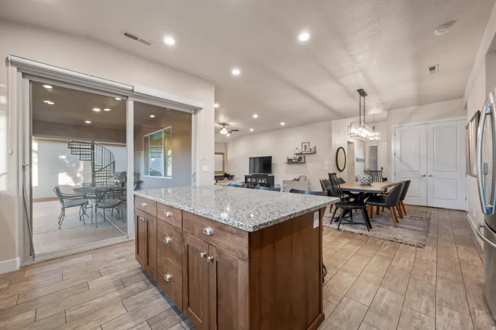 Kitchen with a kitchen island, wood finish floors, light stone counters, wood finish cabinets, and open floor plan