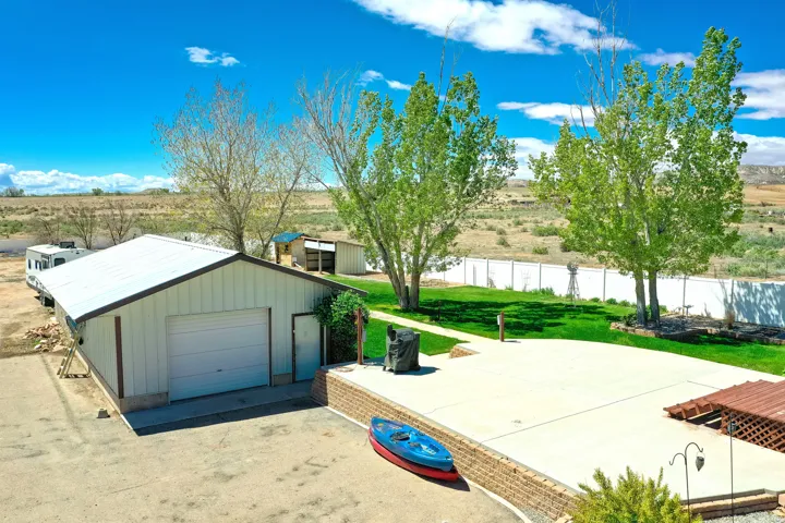 Detached garage with a white roll-up door, side entrance, and metal roof
