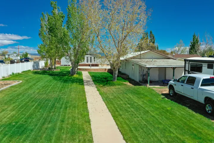 Expansive front yard with a concrete pathway leading to the residence