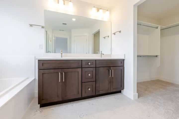 Dual vanity with dark wood-finish cabinetry, white countertop, and integrated sink