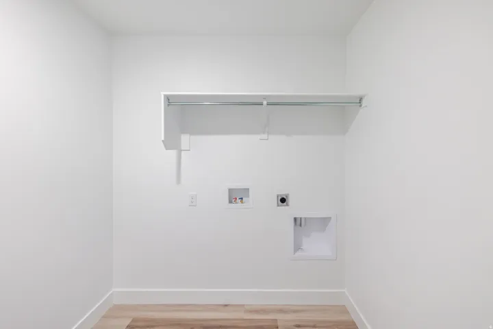 Dedicated laundry area featuring a wall-mounted shelf, hanging rod, and utility hookups
