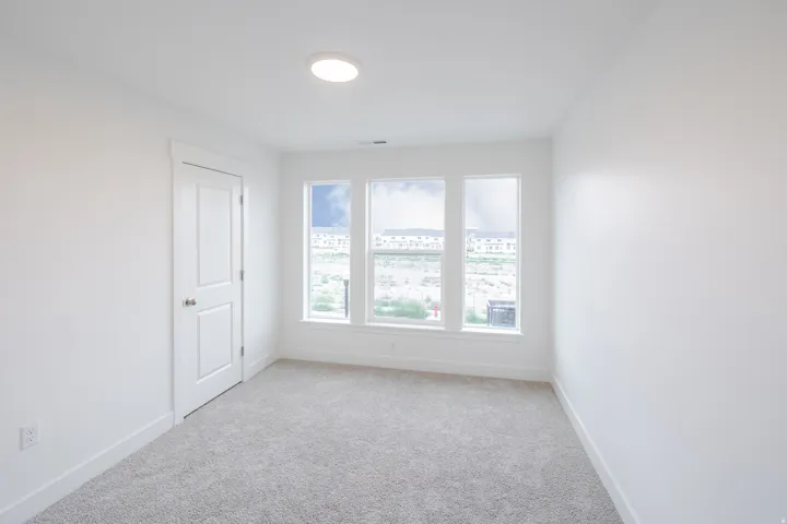 Recessed ceiling light, white walls, light gray carpet, and three windows