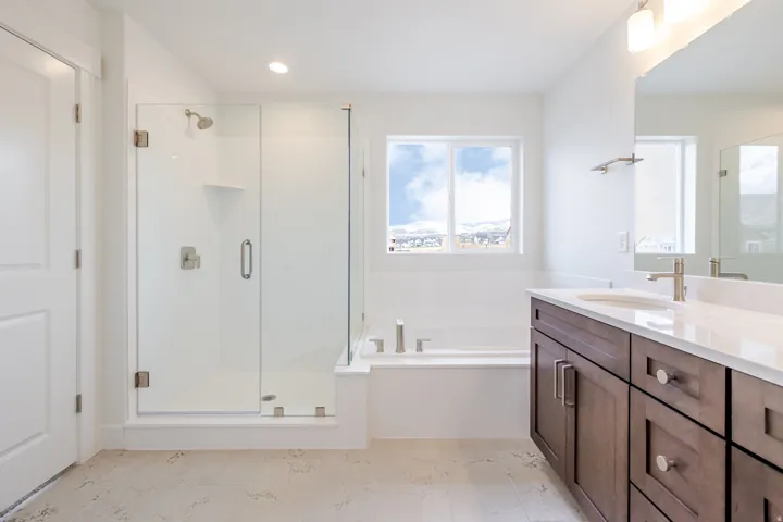 Spacious bathroom featuring a glass-enclosed shower, built-in bathtub, and a double vanity with wood-finish cabinetry