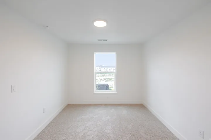Carpeted room featuring a single window, recessed ceiling light, and white walls