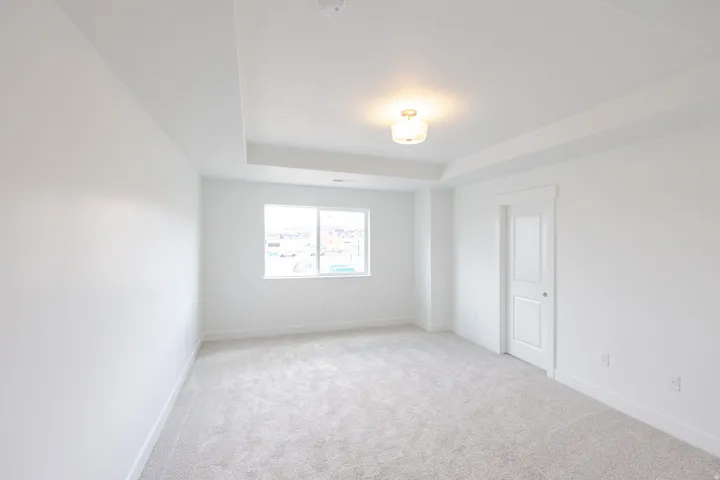 Tray ceiling with recessed lighting, wall-to-wall carpeting, and a window with white trim