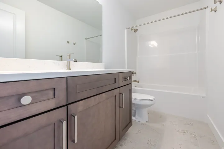 Integrated vanity with wood-finish cabinetry, light-toned countertop, and undermount sink