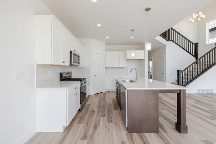 Modern kitchen featuring white cabinetry, stainless steel appliances, a center island with sink, and wood-finish flooring