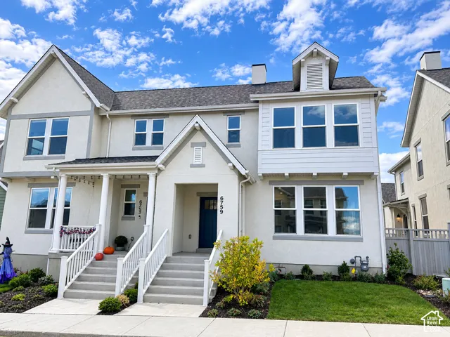 Stucco exterior with gabled roof lines, multiple multi-pane windows, a recessed entry, and dual concrete staircases with white railings