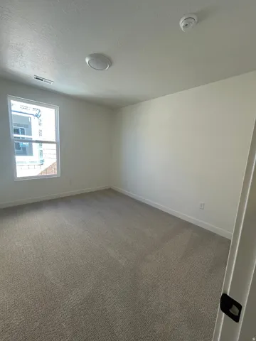 Carpeted room featuring a single window, white baseboards, and a flush-mount ceiling light