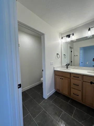 Bathroom featuring a dual vanity with light wood-finish cabinetry, white countertops, and black fixtures