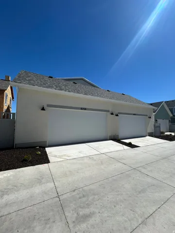 Stucco exterior featuring a two-car garage with overhead doors and exterior wall sconces