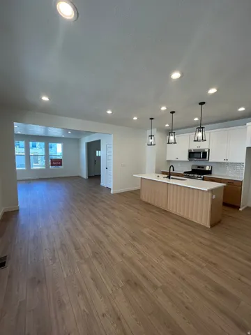 Open-concept main living area featuring wood-finish flooring, recessed lighting, and a kitchen island with pendant lights