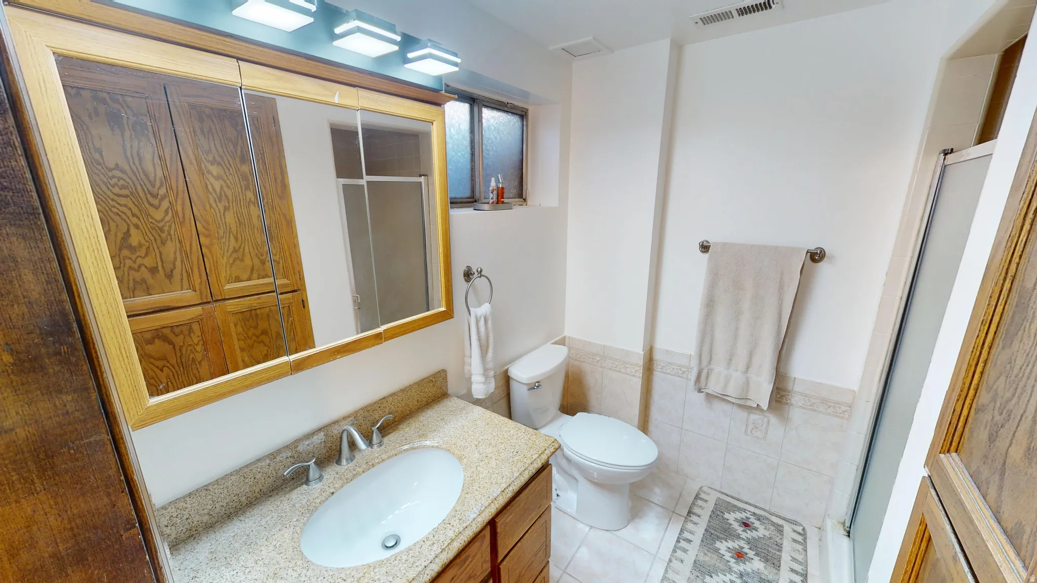 Bathroom featuring a vanity with a light-toned countertop, a rectangular mirror with a wooden frame, and overhead vanity lighting