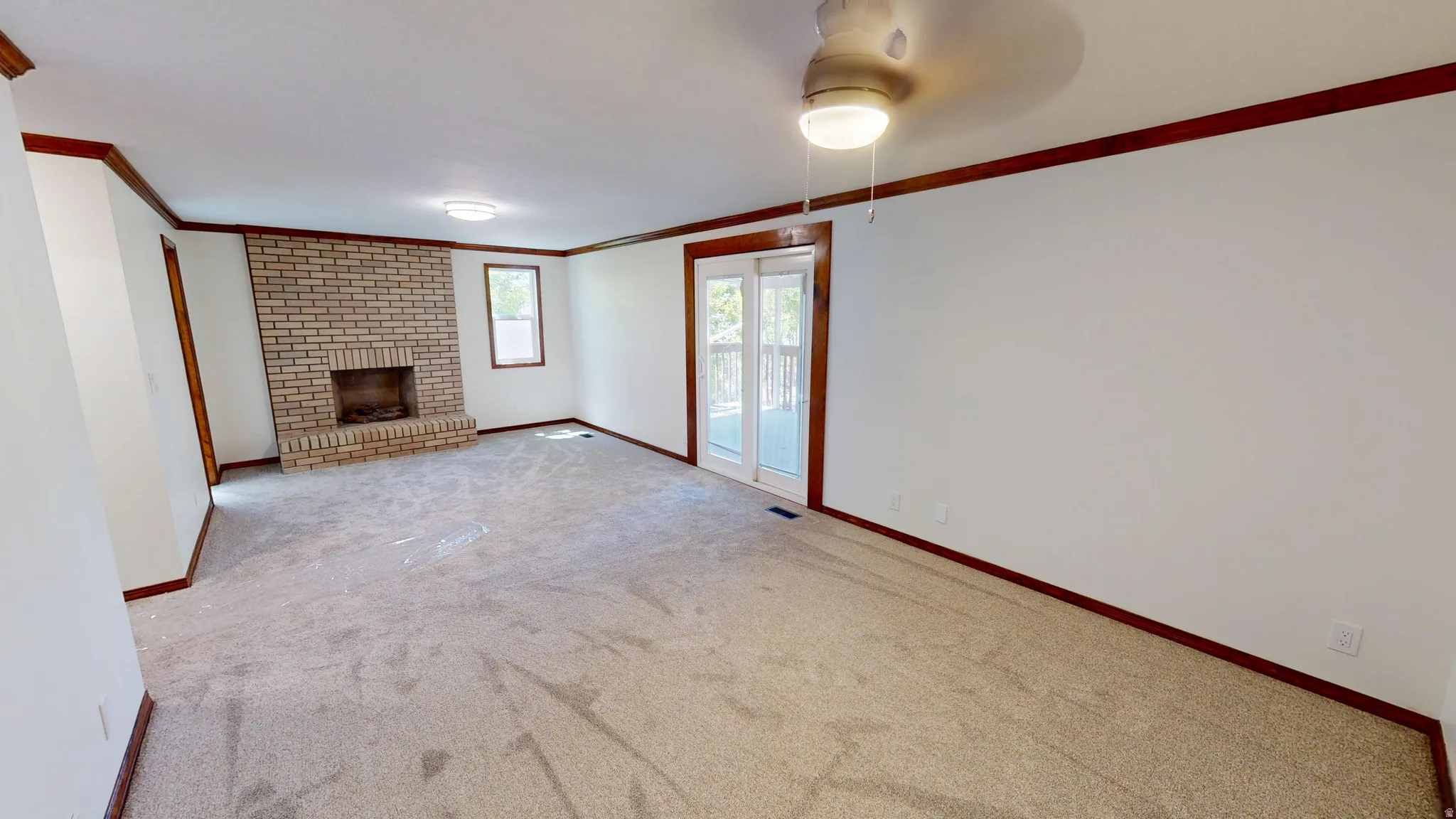 Master Bedroom featuring light-colored carpeting, a brick fireplace, and white walls with dark wood trim