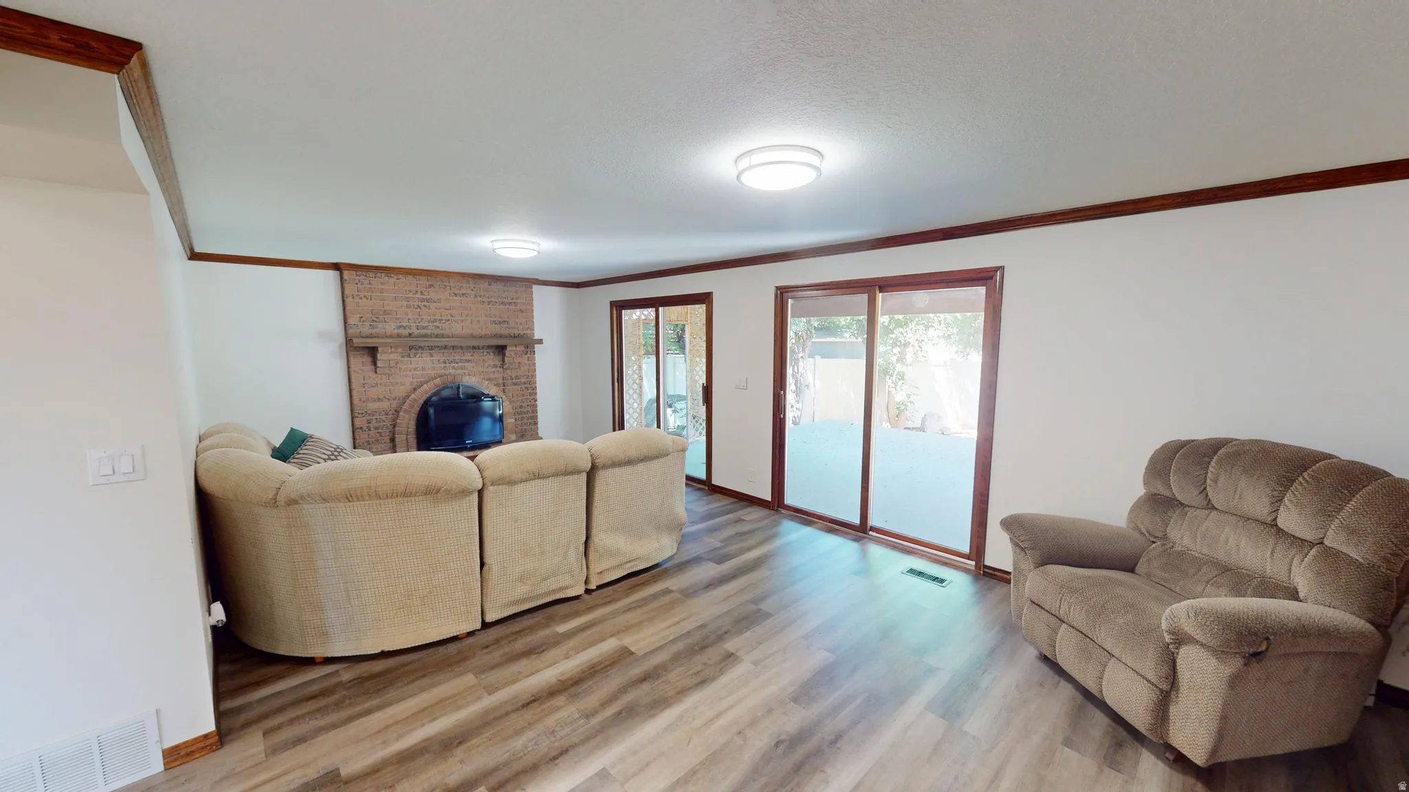 Living area featuring wood-finish flooring, a brick fireplace, and dual sliding glass doors