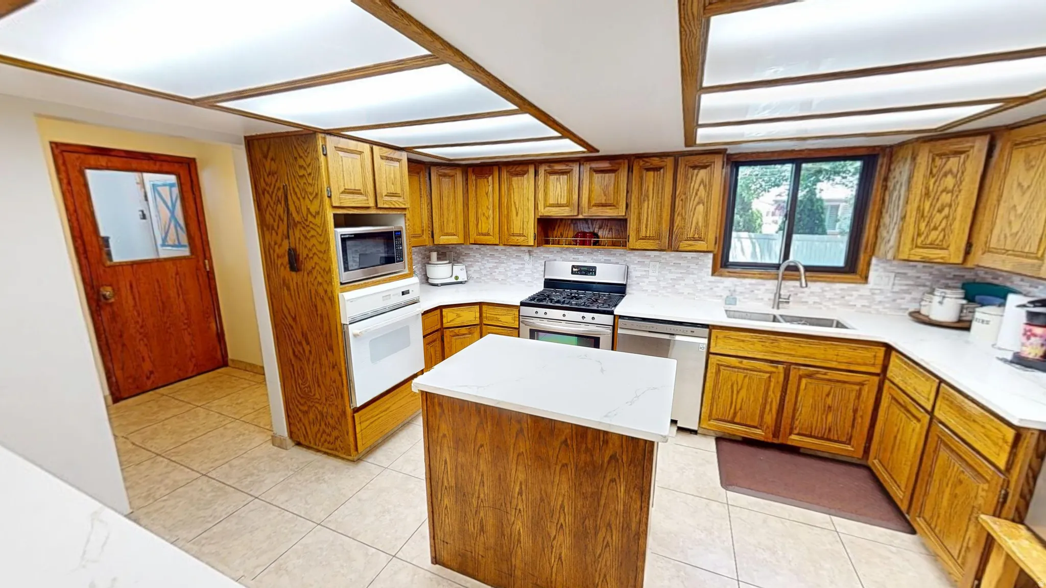 Kitchen featuring wood cabinetry, white countertops, tile flooring, a built-in oven, and a center island