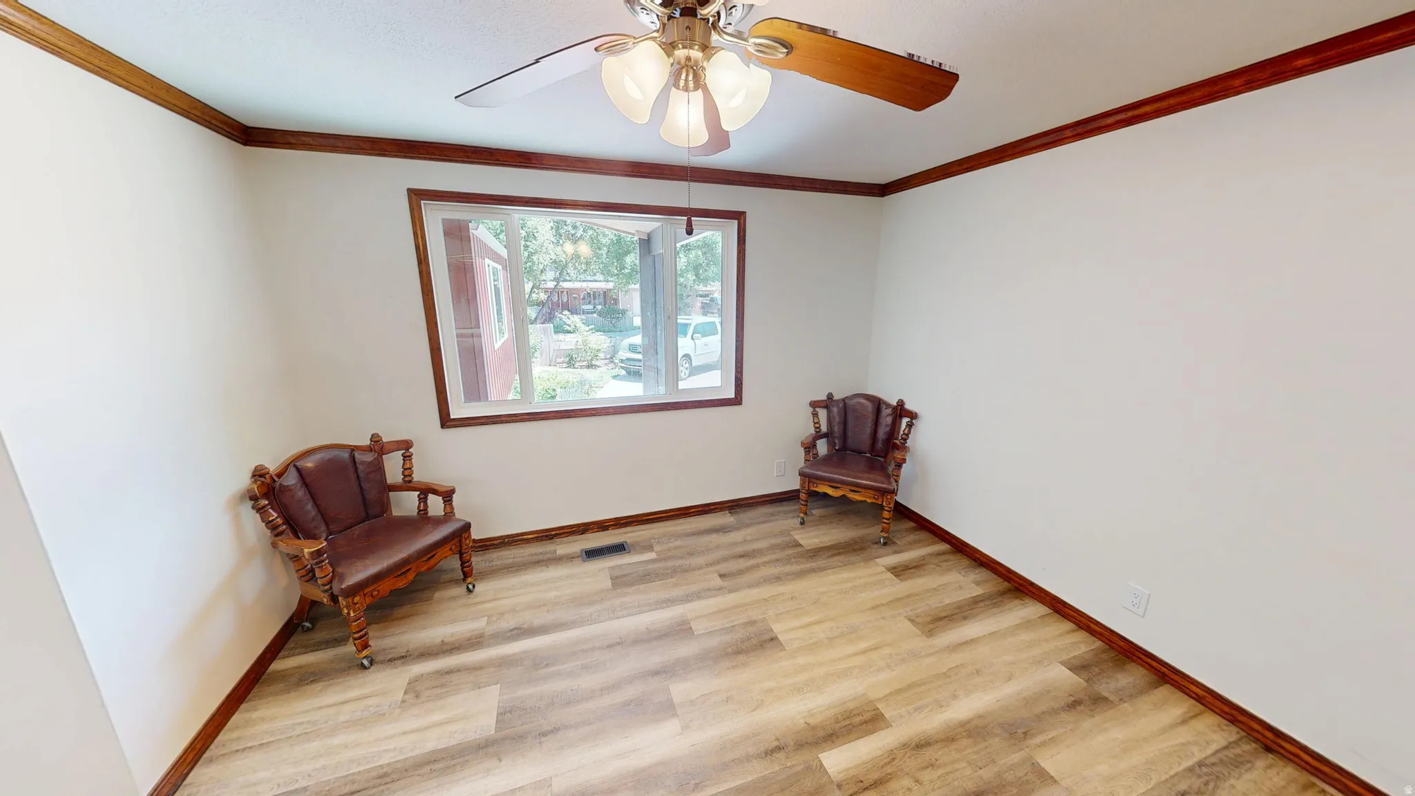 Spacious room featuring wood-finish flooring, white walls, and dark wood trim