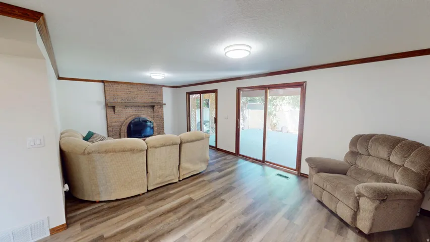 Living area featuring wood-finish flooring, a brick fireplace, and dual sliding glass doors