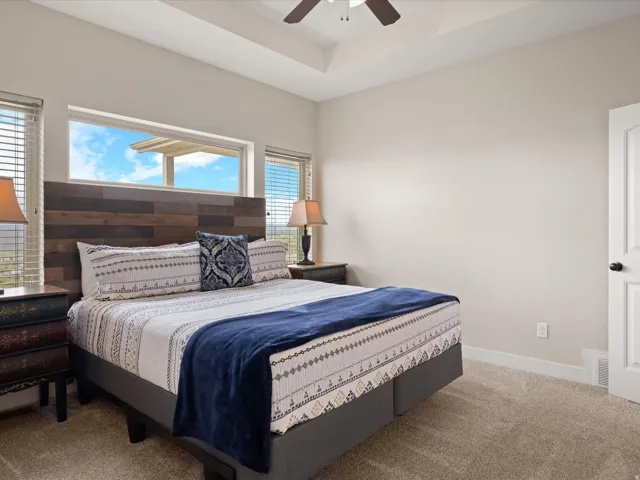 Tray ceiling with a ceiling fan, light neutral wall color, and plush carpet flooring