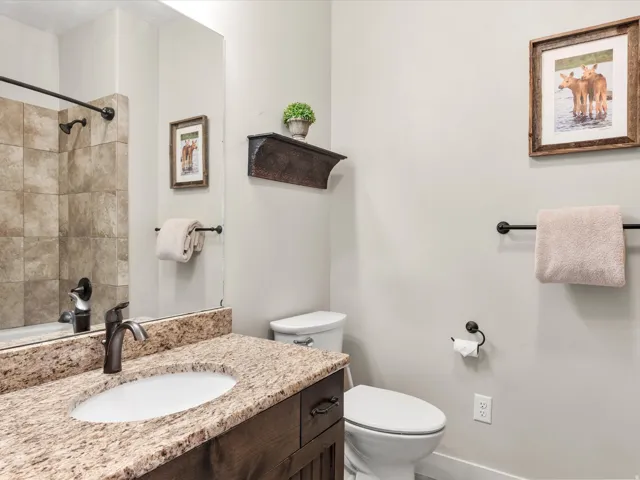 Bathroom featuring a vanity with a light-toned stone countertop, integrated sink, dark wood-finish cabinetry, and oil-rubbed bronze fixtures