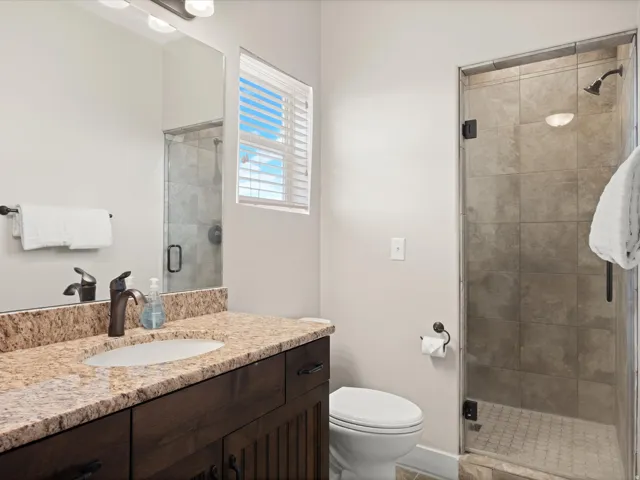 Bathroom featuring a rich wood-finish vanity with a granite countertop, undermount sink, and bronze-finish faucet