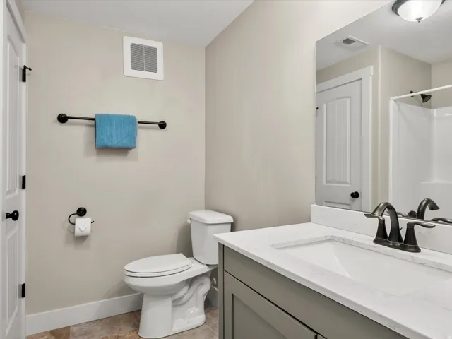 Bathroom vanity with a white countertop and integrated sink, bronze-finish faucet, and coordinating bronze hardware