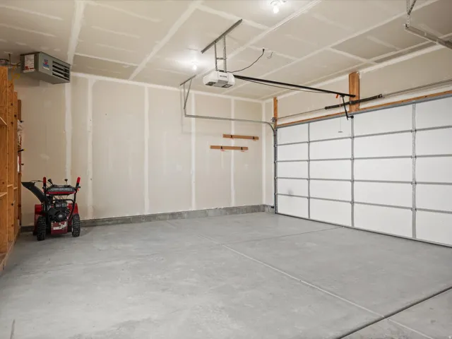 Spacious garage featuring a concrete floor, overhead lighting, and an automatic garage door opener