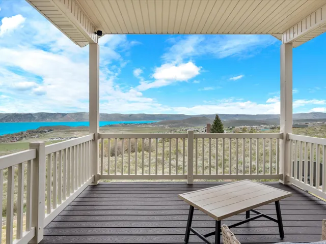 Covered outdoor deck with composite decking and light-colored railings, offering expansive scenery with a prominent body of water and distant hills