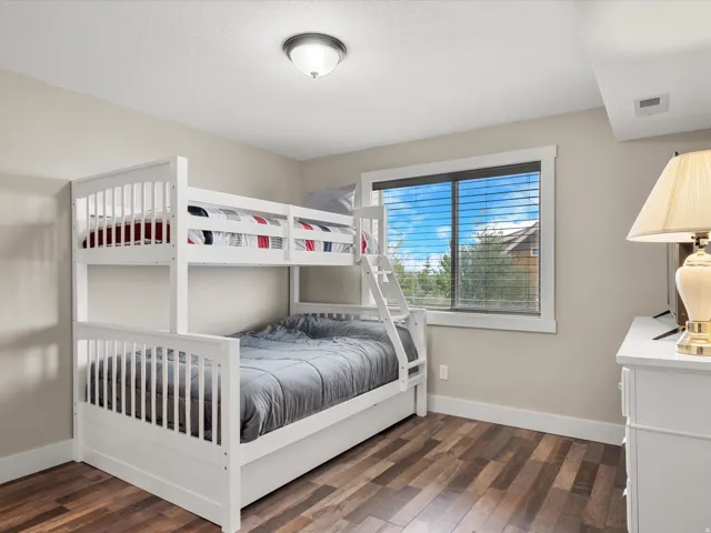 Spacious room featuring wood-finish flooring, a contemporary window with blinds, and a flush-mount ceiling light fixture
