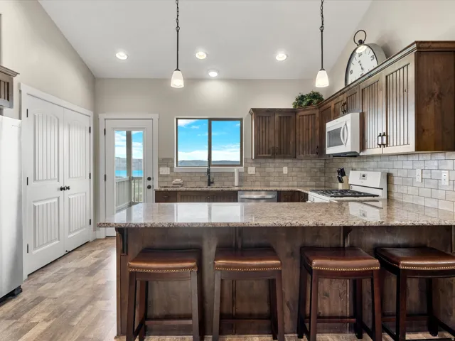 Kitchen featuring wood-finish flooring, wood cabinetry with paneled inserts, stone countertops, and a subway tile backsplash