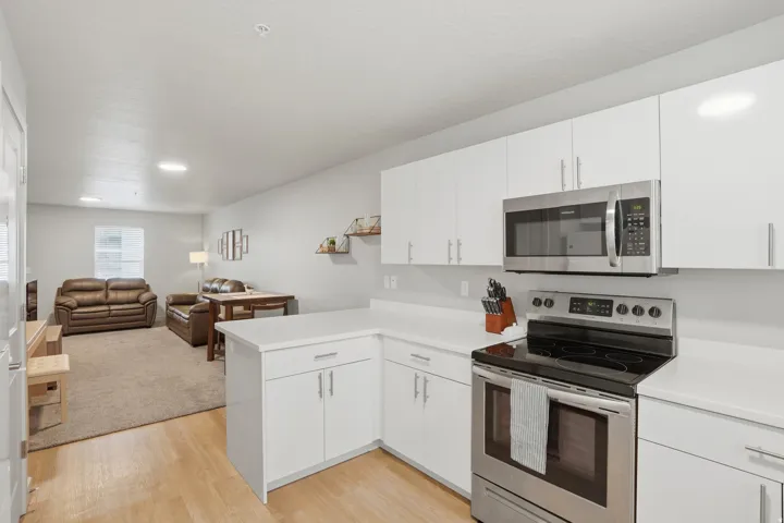 Kitchen featuring wood-finish flooring, white cabinetry, stainless steel appliances, and white countertops