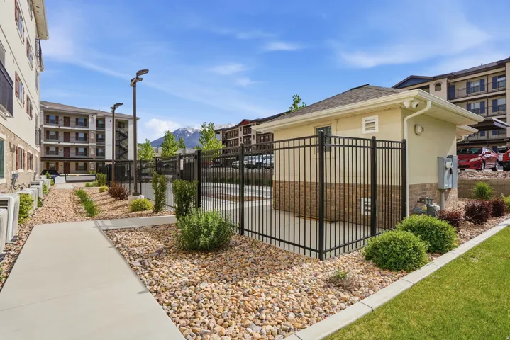 Manicured grounds featuring a concrete pathway, decorative rock landscaping, and mature shrubbery