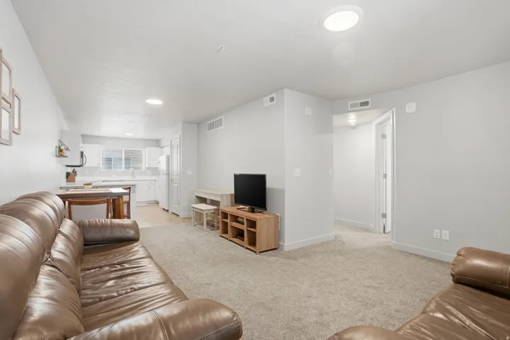 Open-concept living space featuring light gray walls, carpet flooring, and recessed ceiling lighting